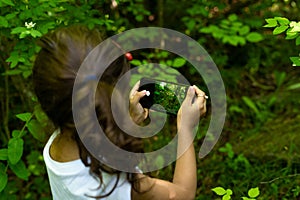 small brunette with pony tail girl taking photos of park and nature using a cell phone