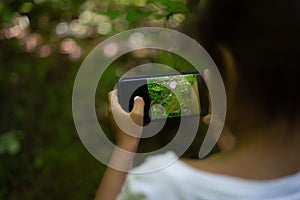 small brunette with pony tail girl taking photos of park and nature using a cell phone