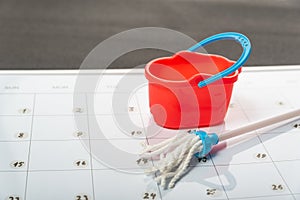 Small bucket and mop on calendar. Planned cleanup. Concept of spring general cleaning