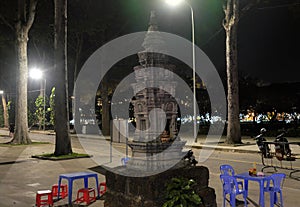 Small Buddhist altar in the park. A table and several plastic chairs. Lantern light