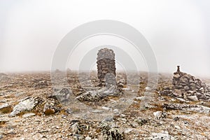 Small built stone towers among stones with moss in the foggy landscape