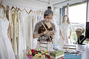 Small Business of Asian women Fashion Designer Working With Wedding Dresses at clothing store