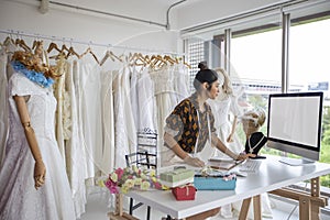 Small Business of Asian women Fashion Designer Working With Wedding Dresses at clothing store