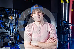 Small business and bicycle transport service. Portrait of a young man in a cap posing against the backdrop of a bicycle workshop a