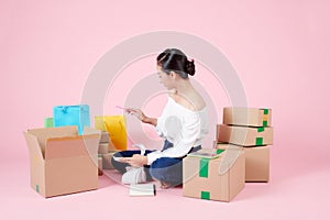 Small business entrepreneur or Asian businesswoman sitting and packing parcel boxes on floor isolated on white background