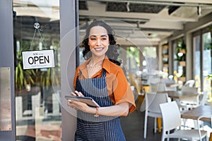 Small business entrepreneur at cafe entrance using digital tablet