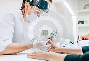 Small business existence at COVID-19 lockdown concept. Professional manicure master in Transparent Safety Face Shield using