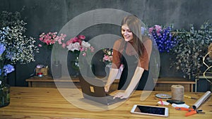 Small business florist in a flower shop receives a message about a new order. Joyful emotions from future profits.