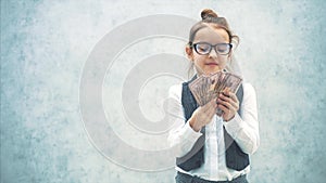 The small business lady stands on a gray background with dollars in her hands. During this, she waves a bundle of money