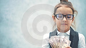 The small business lady stands on a gray background with dollars in her hands. During this, she waves a bundle of money