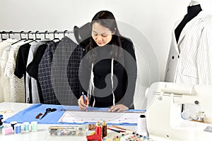 Small business owner, Dressmaker designer making pattern and measure garment. photo