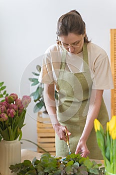 Small business. The owner of a flower shop in a green apron collects a bouquet of fresh flowers for delivery. The