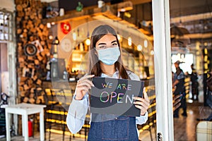 Small business owner smiling while holding the sign for the reopening of the place after the quarantine due to covid-19. Woman