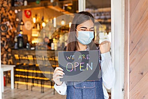 Small business owner smiling while holding the sign for the reopening of the place after the quarantine due to covid-19. Woman