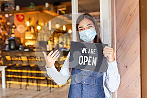 Small business owner smiling while holding the sign for the reopening of the place after the quarantine due to covid-19. Woman