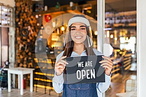 Small business owner smiling while holding the sign for the reopening of the place after the quarantine due to covid-19. Woman