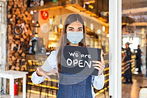 Small business owner smiling while holding the sign for the reopening of the place after the quarantine due to covid-19. Woman