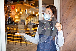 Small business owner smiling while holding the sign for the reopening of the place after the quarantine due to covid-19. Woman