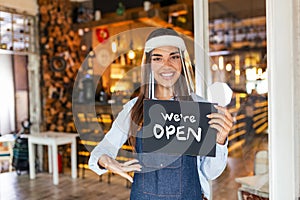 Small business owner smiling while holding the sign for the reopening of the place after the quarantine due to covid-19. Woman