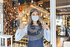 Small business owner smiling while holding the sign for the reopening of the place after the quarantine due to covid-19. Woman