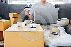 Small business parcel for shipment to client, Young man received online shopping parcel opening boxes and buying items by credit