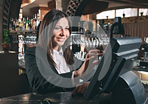 Small business, people and service concept - happy woman or waiter or manager in apron at counter with cashbox working