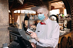Small business, people and service concept. man or waiter in medical mask at counter with cashbox working at bar or