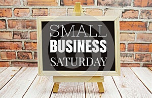 Small Business Saturday text on the blackboard set on wooden floor and brick background