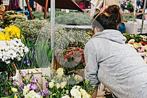 A small business for selling flowers. Street shop. A young girl is a salesman doing work. There are different kinds of