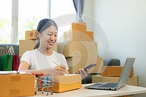 Small business startup, SME owner, young Asian woman checking online orders, selling products, working with boxes,