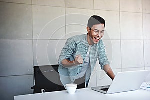 Small Business and Successful Concept. Young Asian Businessman Glad to recieve a Good News or High Profits from Computer Laptop,