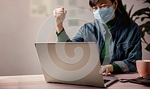 Small Business and Successful during Coronavirus Concept. blurred Gladful Business Woman wearing Mask, Working on Computer Laptop