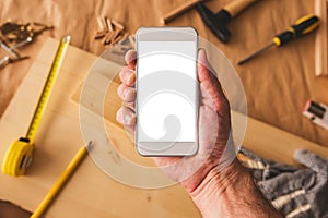 Small business woodwork entrepreneur holding smartphone with mock up screen