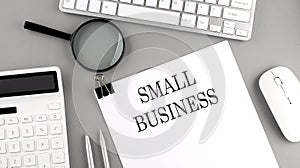 SMALL BUSINESS written on paper with office tools and keyboard on the grey background