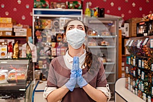 Small businesses during the pandemic. A female worker in a medical mask and rubber gloves, spreads her hands and looks up with