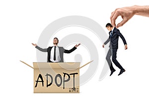 Small businessman sitting in box marked `Adopt` and looking up, while giant hand brings another man