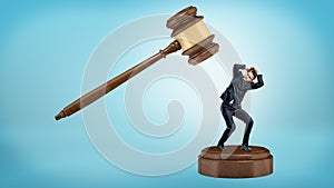 A small businessman tries to avoid a giant gavel strike while standing on a sound block.