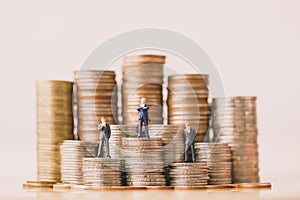 Small businessmans figures standing on coins stack. photo