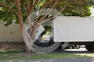 Small cab over semi truck with open cab and box trailer independently makes repairs at home right under the tree