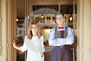 Small cafe owners standng in entrance and waiting for guests