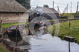 Small canal with its traditional fishing boats, fish smoker in the background