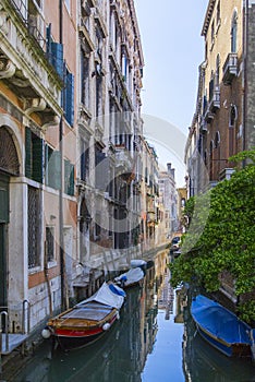 Small canal mid of Venice with traditional wooden boats parked in front of the house entrance