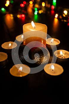 Small candles around a bigger candle and two Christmas globes