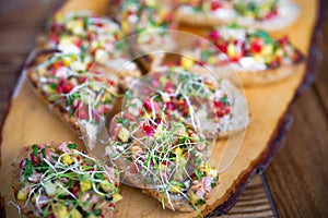 Small capers and fish meat. Bruschetta with baked salmon and basil closeup on rustic wooden table. Dish from italian cuisine.