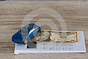 Small car and dollar on car payment concept calculator