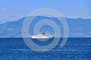 A small car ferry boat sailing on a calm blue sea on a bright summer day in Greece