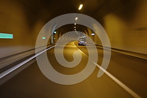 Small car passing through motorway tunnel motion blur