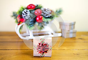 Small cardboard giftbox wrapped in striped ribbon and shiny holiday bow, decorative Christmas sleigh