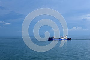 Small cargo container ship sailing through calm, blue sea.