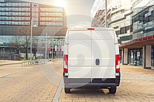 Small cargo delivery van driving in european city central district. Medium lorry minivan courier vehicle deliver package at